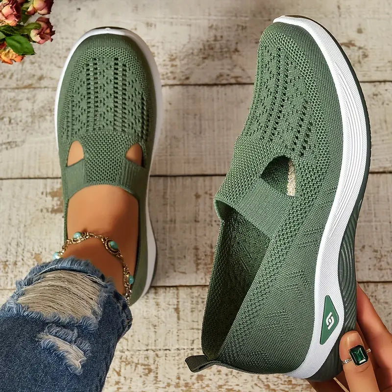 Grüne Damen-Sneaker aus Strickmaterial auf Holzuntergrund, getragen mit zerrissenen Jeans und Schmuck. Bequem, modisch, atmungsaktiv.