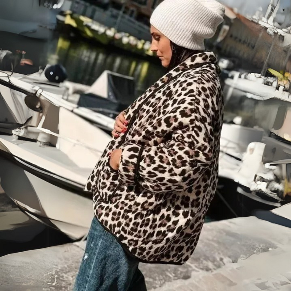 Frau in Leopardenmantel und weißer Mütze steht am Hafen. Modetrend, Wintermode, stilvolle Kleidung, Outdoor, Freizeitlook.