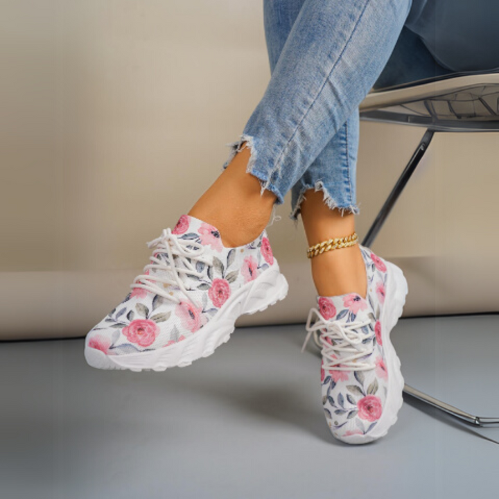 Damen-Sneaker mit Blumenmuster, weiße Sohle, kombiniert mit zerrissenen Jeans. Modische Freizeitschuhe, ideal für Frühling und Sommer.