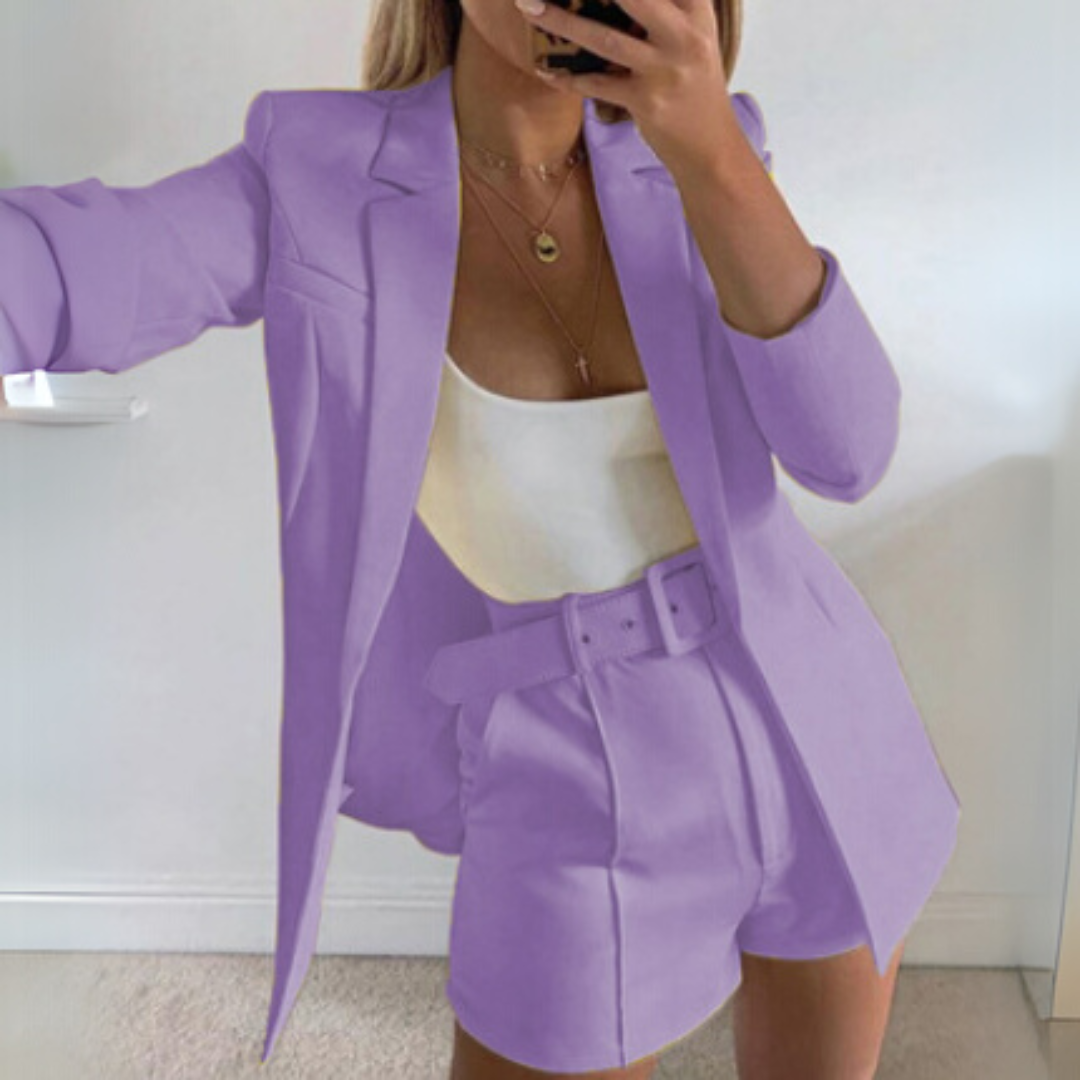 Frau in lila Anzug mit Blazer und Shorts, weißem Top, macht Selfie. Modetrend, eleganter Business-Look, stilvolle Damenbekleidung.
