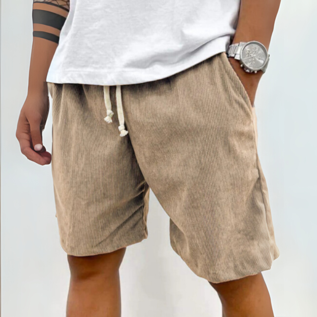 Beige Cord-Shorts für Herren, kombiniert mit weißem T-Shirt und silberner Armbanduhr. Sommermode, lässiger Stil, Freizeitkleidung.