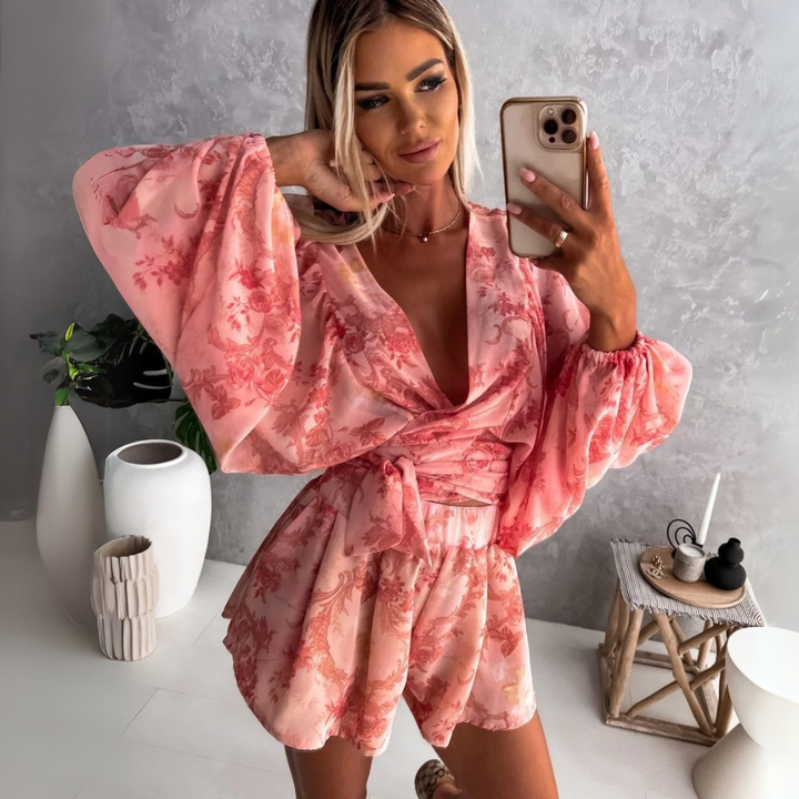 Frau in rosa Blumenkleid macht Selfie, moderne Inneneinrichtung, graue Wand, Holzstuhl, Vasen. Fashion, Selfie, Sommerkleid, Innenraum.