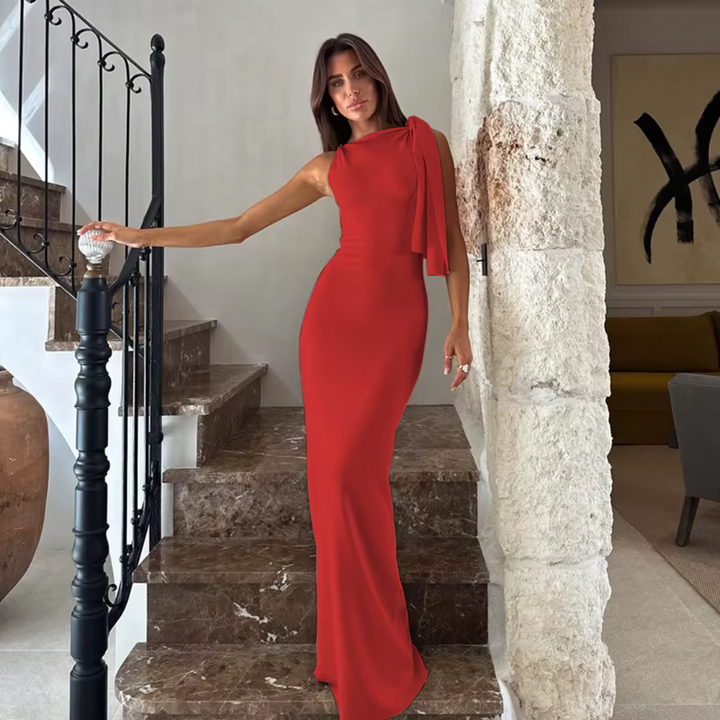 Frau in elegantem roten Abendkleid posiert auf Marmortreppe, modernes Interieur, stilvolle Mode, luxuriöses Design, zeitlose Eleganz.