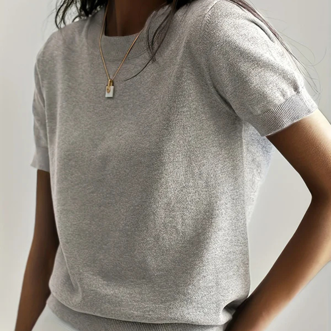 Graues T-Shirt aus Baumwolle, kurzärmelig, getragen von einer Person. Minimalistisches Design, ideal für lässige Mode und Sommeroutfits.