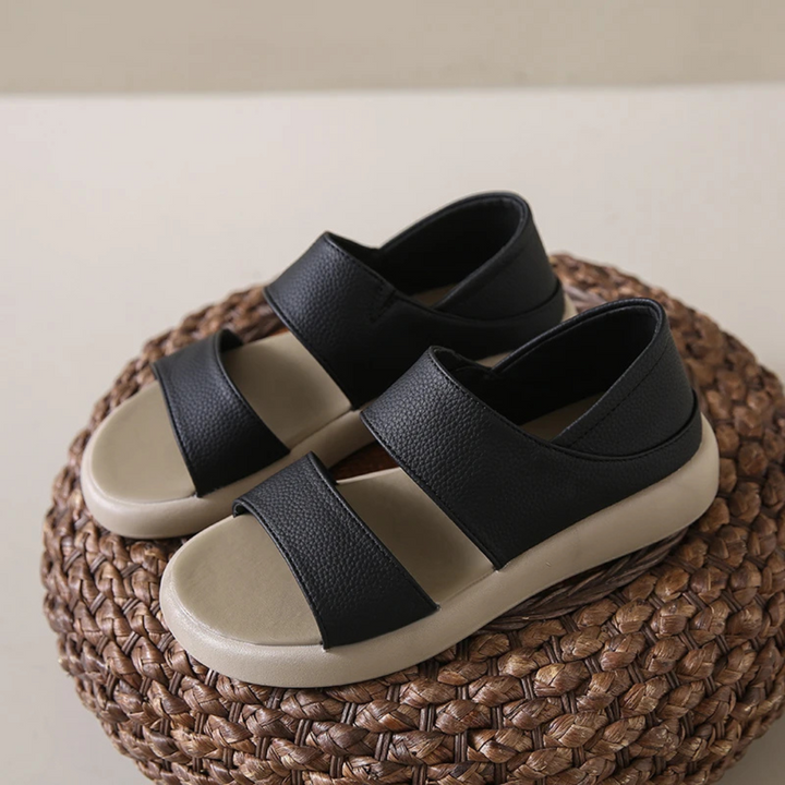 Schwarze Sandalen mit breiten Riemen auf geflochtener Unterlage. Bequeme Sommerschuhe, ideal für Freizeit und Strand. Modische Damen-Sandalen.