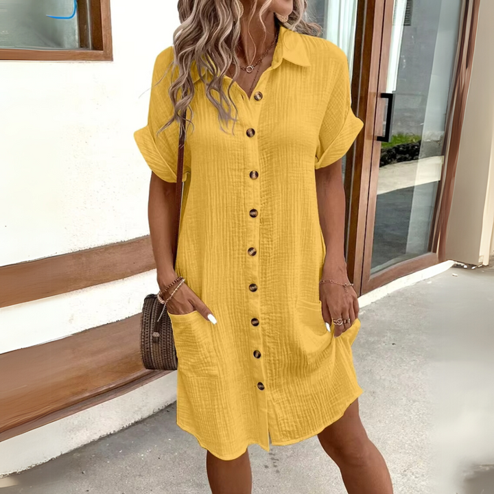 Frau in gelbem Hemdkleid mit Knopfleiste und Taschen, lässiger Sommerlook, modisch, draußen, blondes Haar, moderne Damenmode.