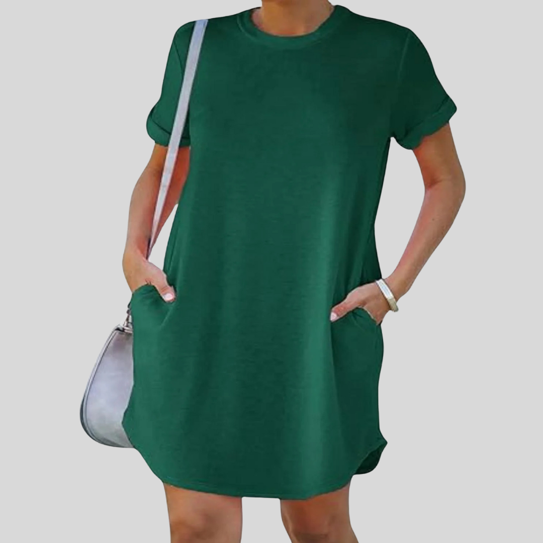 Dame in grünem T-Shirt-Kleid mit kurzen Ärmeln und Taschen, trägt eine graue Umhängetasche. Modetrend, lässiger Sommerlook, bequemes Outfit.