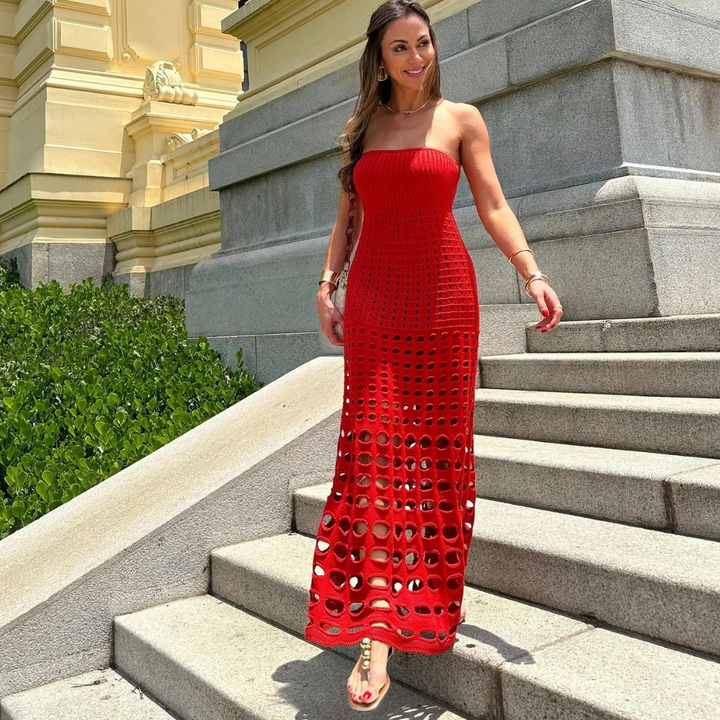 Frau in rotem, gehäkeltem Kleid auf Steintreppe vor historischer Architektur. Sommermode, elegantes Design, stilvolle Kleidung.