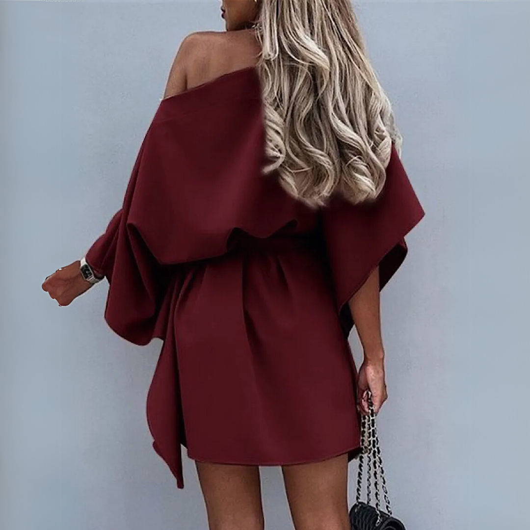 Frau in schulterfreiem, weinrotem Kleid mit langen, blonden Haaren, hält schwarze Handtasche. Elegante Mode, Abendkleid, stilvoller Look.