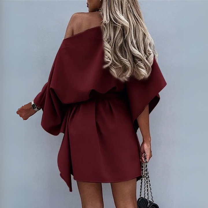 Frau in schulterfreiem, weinrotem Kleid mit langen, blonden Haaren, hält schwarze Handtasche. Elegante Mode, Abendkleid, stilvoller Look.