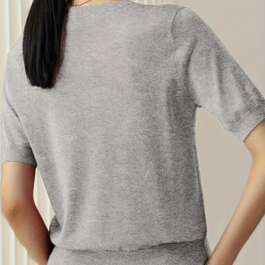 Frau in grauem T-Shirt aus Baumwolle, Rückansicht. Modetrend, lässiger Stil, bequeme Kleidung. Ideal für Alltag und Freizeit.