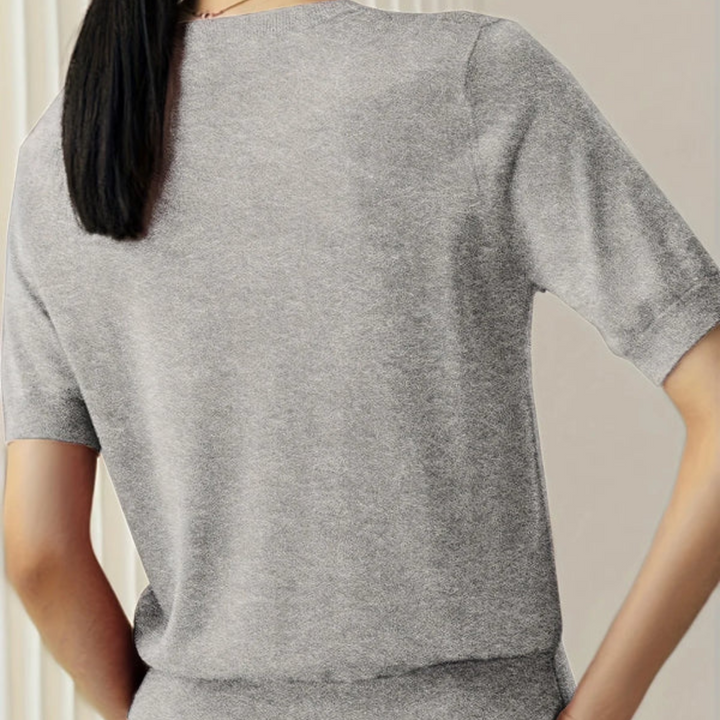 Frau in grauem T-Shirt aus Baumwolle, Rückansicht. Modetrend, lässiger Stil, bequeme Kleidung. Ideal für Alltag und Freizeit.