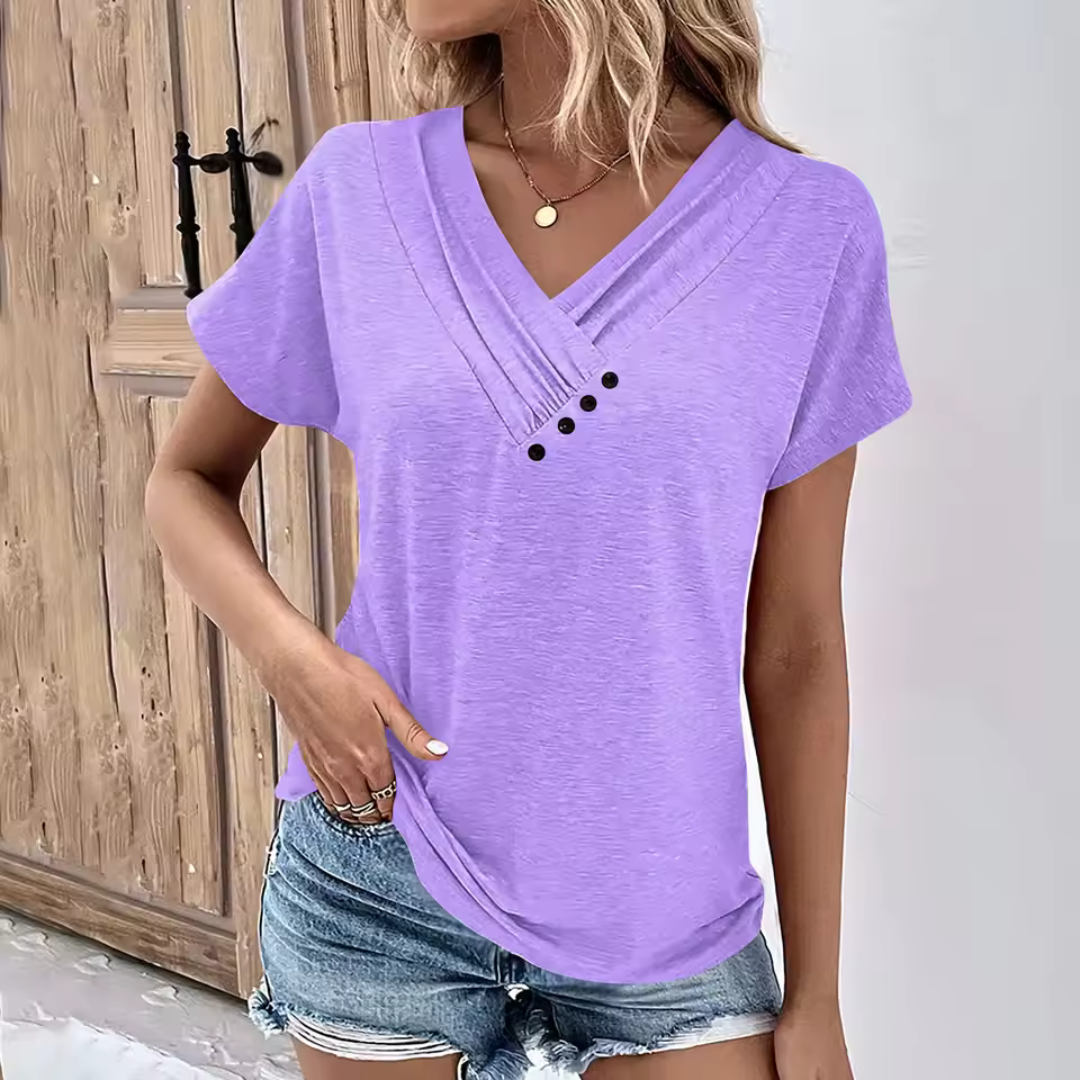 Frau in lila V-Ausschnitt-T-Shirt mit Knöpfen, kombiniert mit Jeansshorts. Sommermode, lässiger Stil, trendige Damenbekleidung.