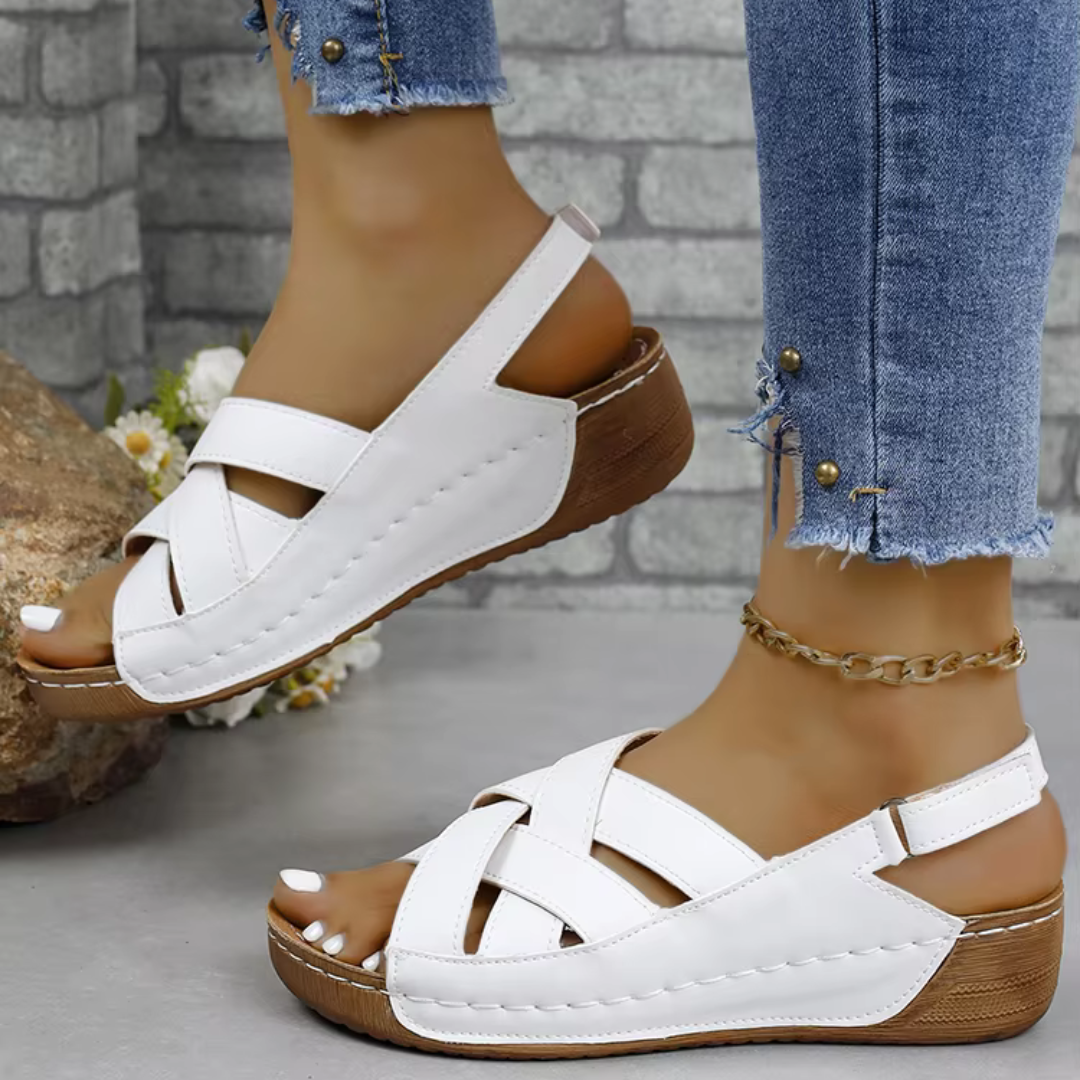 Weiße Damen-Sandalen mit Keilabsatz und Kreuzriemen, getragen mit Jeans. Bequeme Sommerschuhe, ideal für Freizeit und Alltag.