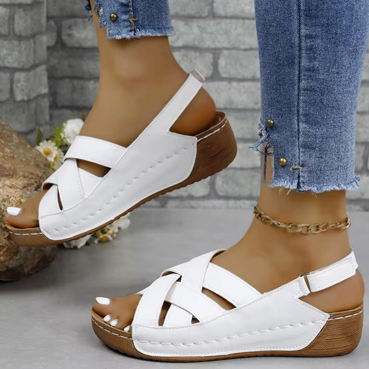 Weiße Damen-Sandalen mit Keilabsatz und Kreuzriemen, getragen mit Jeans. Bequeme Sommerschuhe, ideal für Freizeit und Alltag.