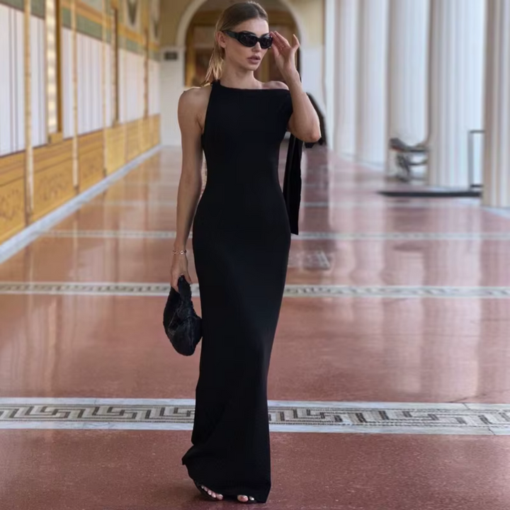 Elegante Frau in schwarzem Abendkleid und Sonnenbrille, läuft in einem luxuriösen, säulengeschmückten Korridor. Mode, Abendgarderobe, Stil.