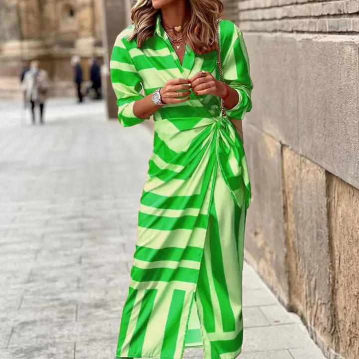 Frau in grün-weiß gestreiftem Kleid auf städtischer Straße, modisches Outfit, elegantes Design, Frühlingsmode, trendige Damenbekleidung.