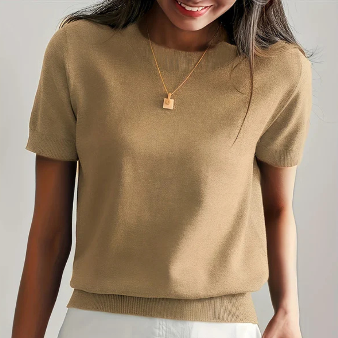 Frau trägt beigefarbenen Strickpullover und goldene Halskette, lächelt. Modetrend, Damenbekleidung, eleganter Freizeitlook.