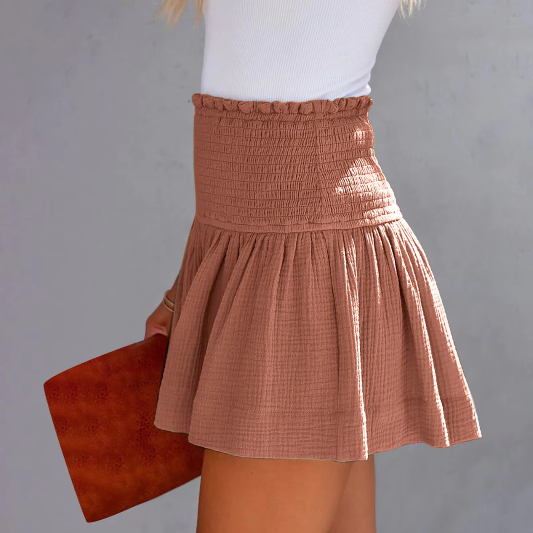 Frau in weißem Top und braunem, gerafftem Rock hält eine braune Clutch. Modetrend, Sommeroutfit, Damenmode, stilvoller Look.