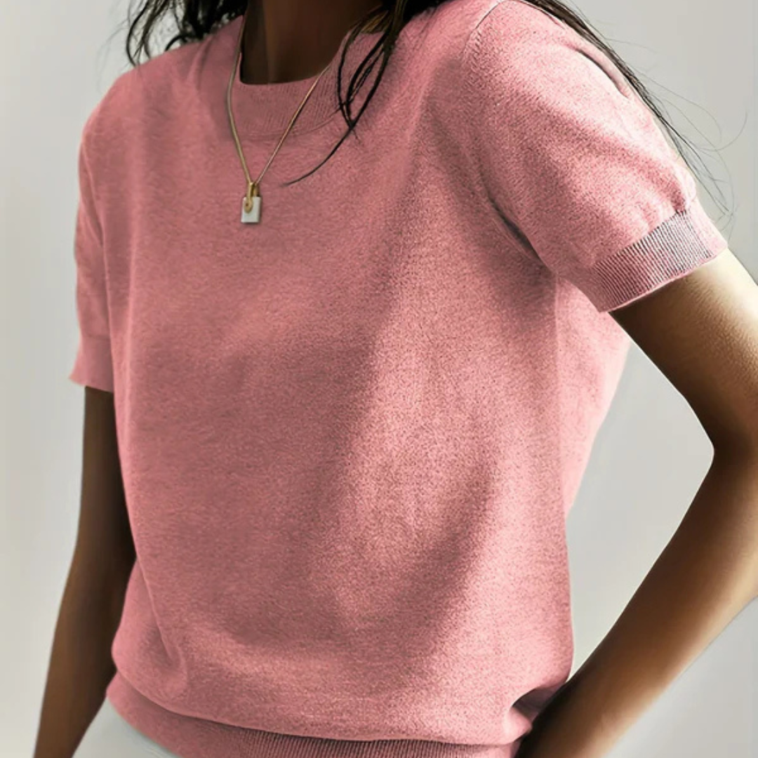 Frau in rosa T-Shirt aus Baumwolle, trägt goldene Halskette. Modetrend, Damenbekleidung, lässiger Stil, Sommermode, elegantes Design.