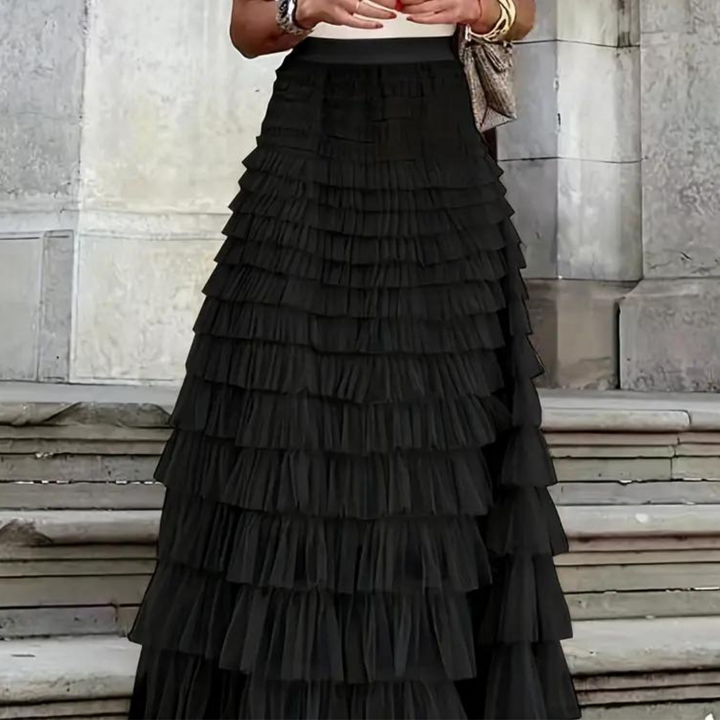 Elegantes schwarzes Stufenrock-Kleid vor steinernen Treppen, modisches Abendoutfit, ideal für formelle Anlässe und stilvolle Events.