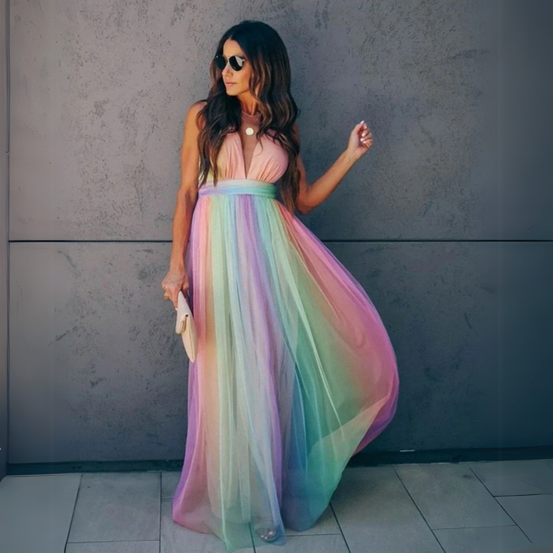 Frau in langem, ärmellosem Regenbogenkleid vor grauer Wand, trägt Sonnenbrille und hält eine Clutch. Elegante Mode, Sommerkleid, Streetstyle.