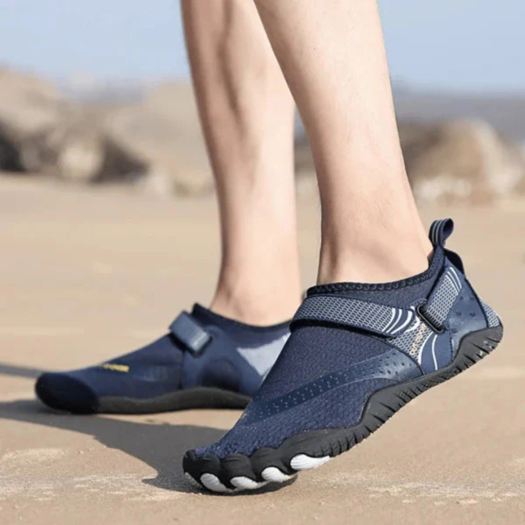 Beine in blauen Barfußschuhen am Strand, ideal für Outdoor-Aktivitäten. Leichte, flexible Wasserschuhe für Herren, perfekt für Sommer und Sport.
