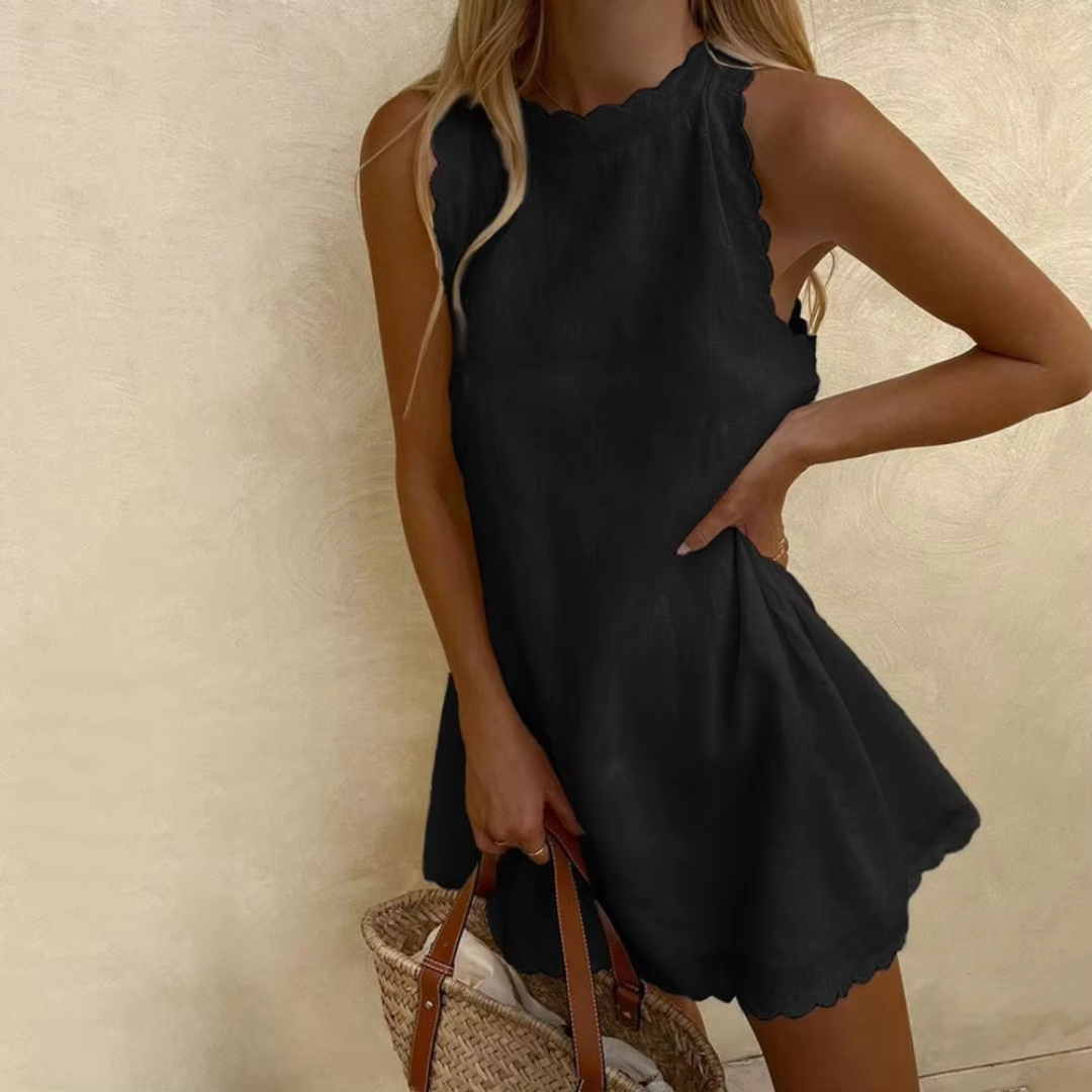 Blonde Frau in schwarzem Sommerkleid mit gewelltem Saum, hält einen geflochtenen Korb. Elegantes, lässiges Outfit für warme Tage.