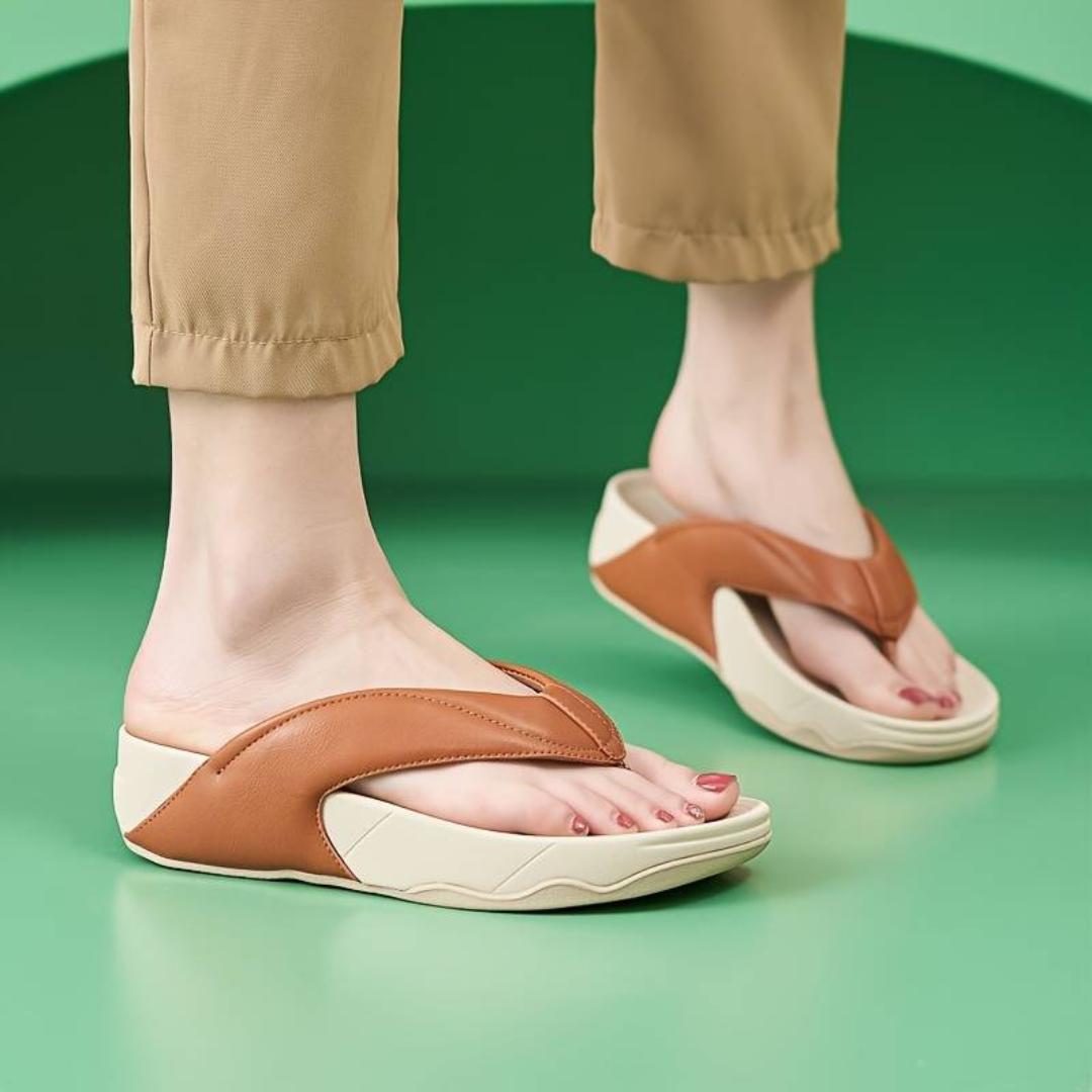 Beige Damen-Sandalen mit braunen Riemen auf grünem Hintergrund. Bequeme Sommerschuhe, modisch und stilvoll. Ideal für Freizeit und Strand.