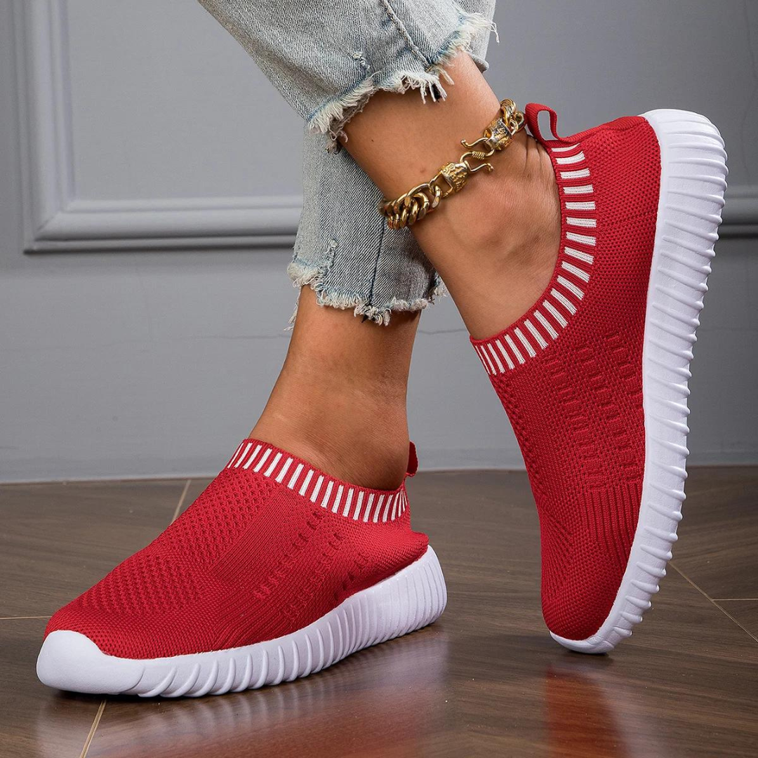 Rote Damen-Sneaker mit weißer Sohle, gestricktes Obermaterial, getragen mit hellblauen Jeans. Bequeme, modische Freizeitschuhe für den Alltag.