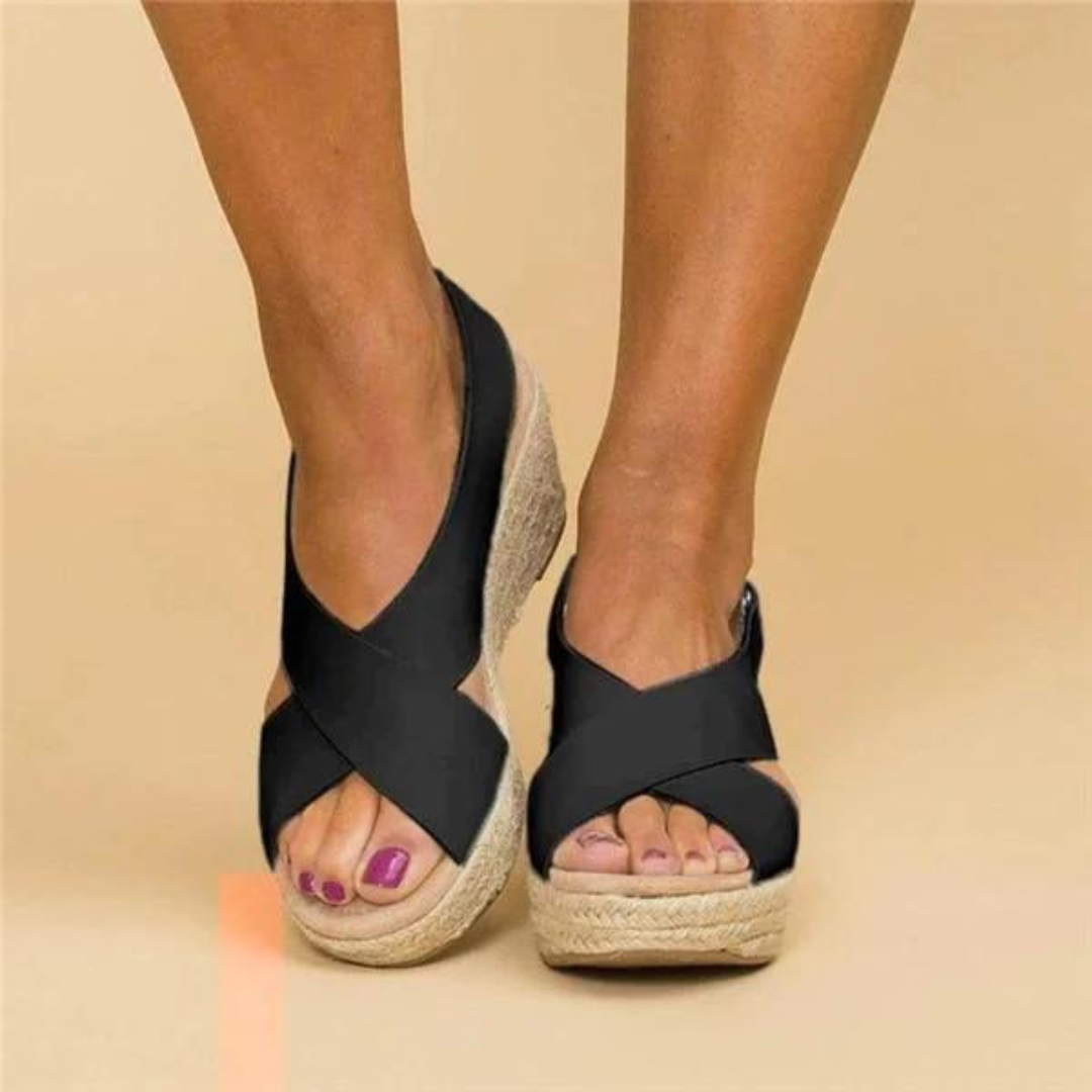 Schwarze Damen-Wedges mit Bastsohle, offene Zehen, gekreuzte Riemen, modische Sommerschuhe, Nahaufnahme, beige Hintergrund.