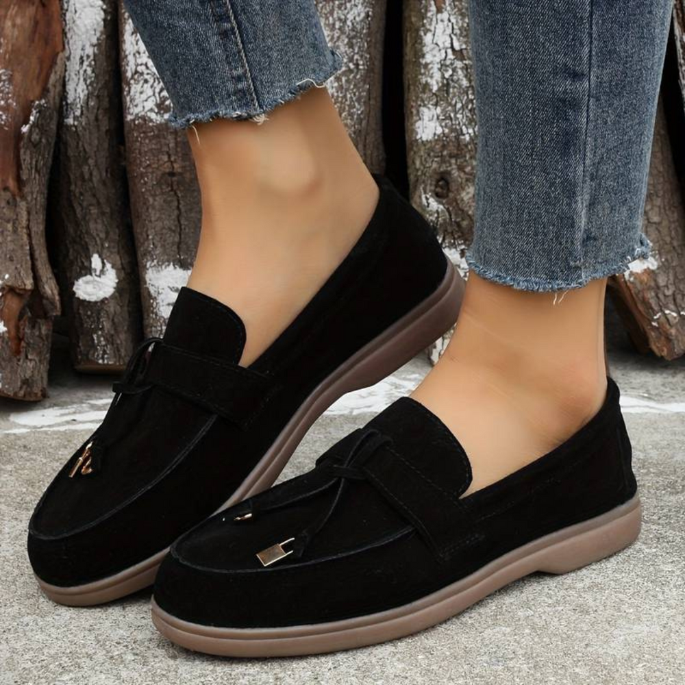 Schwarze Damen-Loafer aus Wildleder mit Quasten, getragen mit blauen Jeans. Bequeme, modische Schuhe für den Alltag. Ideal für Herbstmode.