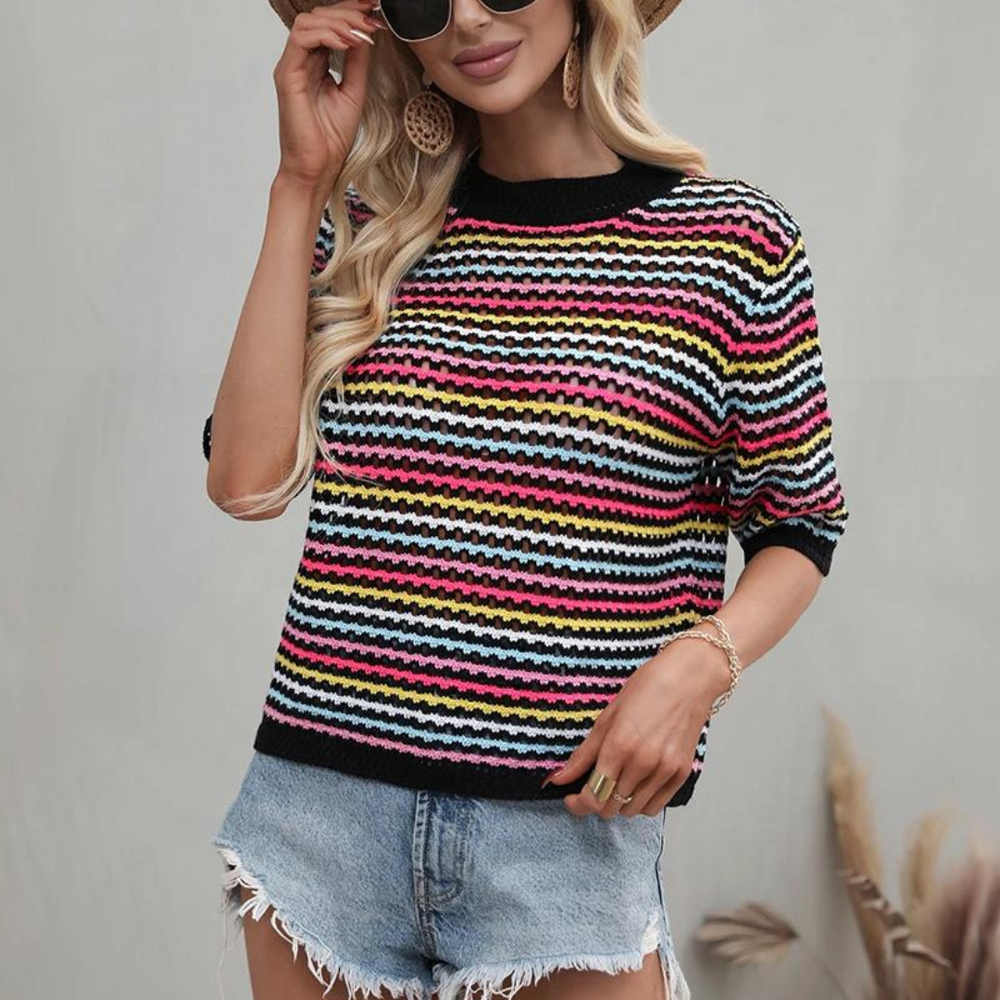 Frau in gestreiftem Pullover und Jeansshorts, trägt Sonnenbrille und Strohhut. Modetrend, Sommeroutfit, lässiger Stil, bunte Streifen.