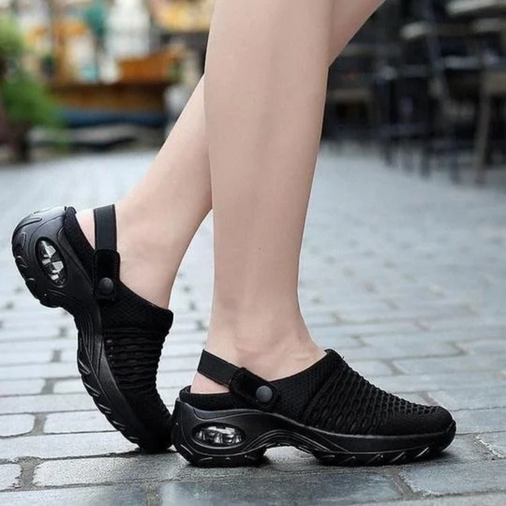 Schwarze Damen-Sneaker mit Luftpolstersohle, atmungsaktivem Mesh-Obermaterial und verstellbarem Riemen, ideal für Komfort und Stil auf Kopfsteinpflaster.