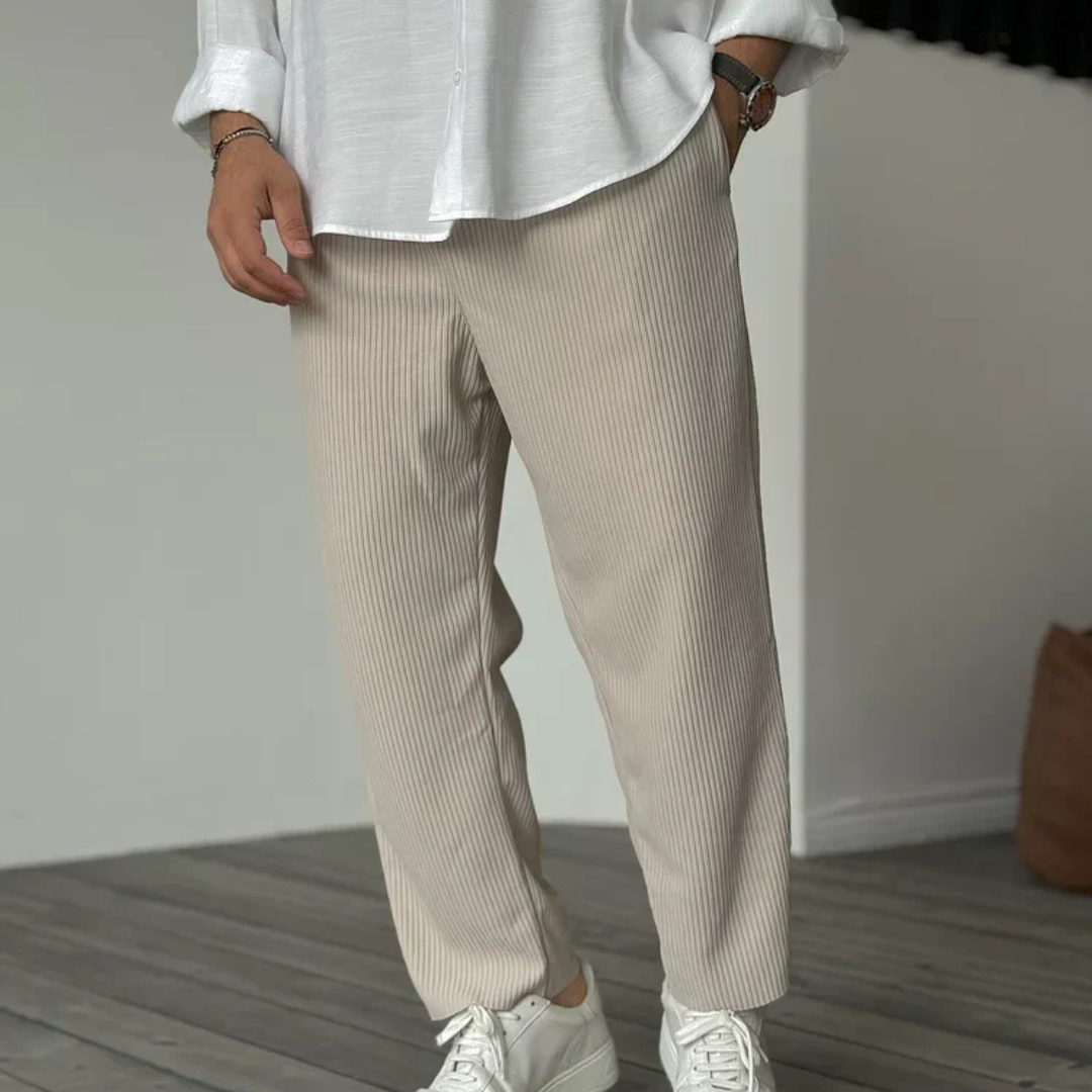 Herrenmode: Mann in beiger, gerippter Hose und weißem Hemd, kombiniert mit weißen Sneakern. Stilvolle Freizeitkleidung für moderne Männer.