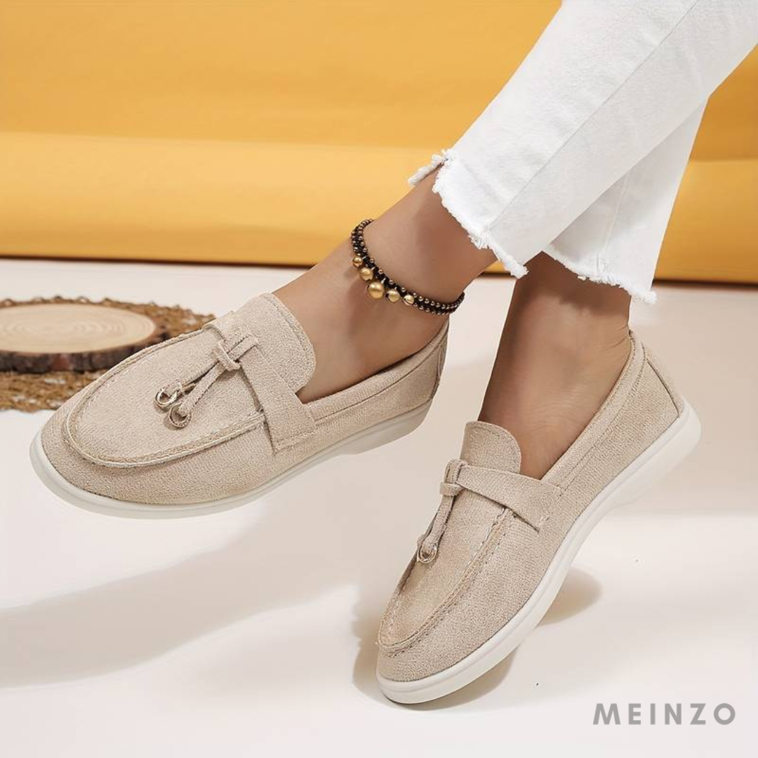 Beige Damen-Loafer aus Wildleder mit dekorativer Schleife, getragen mit weißen Jeans. Modische, bequeme Schuhe für den Alltag.