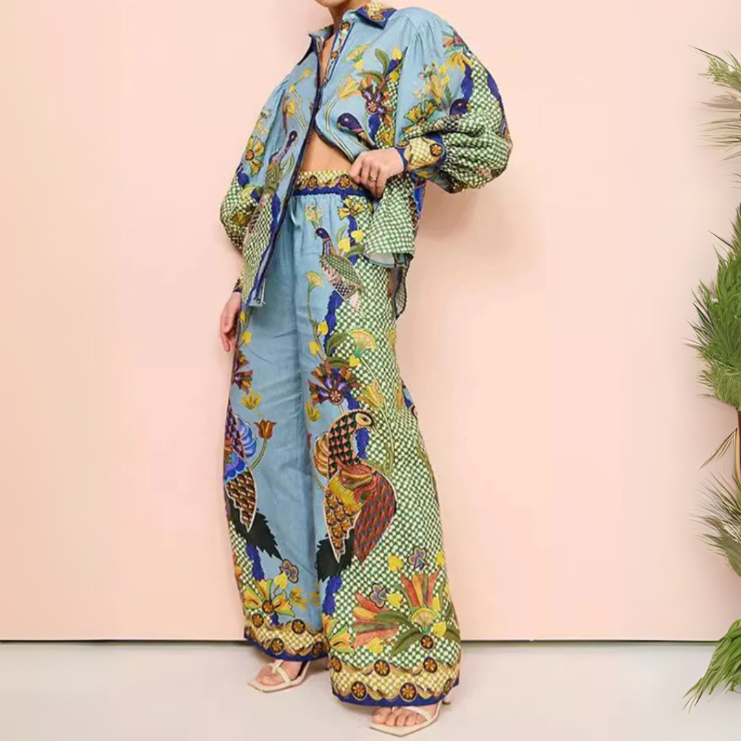 Frau in bunter, floraler Kleidung mit weitem Hemd und Hose, vor rosa Hintergrund. Modetrend, Boho-Stil, auffälliges Design, Sommermode.