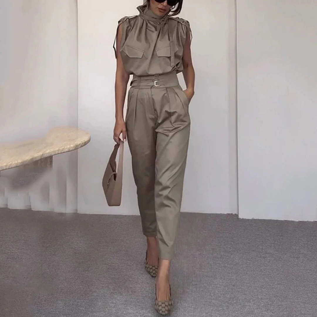 Frau in stilvollem, khakifarbenem Jumpsuit mit Gürtel, trägt braune Handtasche und gemusterte Pumps. Elegante Mode, moderne Damenbekleidung.