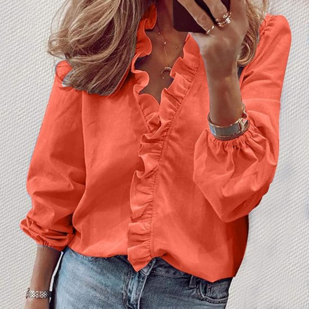 Frau in roter Rüschenbluse und blauer Jeans, hält Smartphone. Modetrend, Damenmode, Freizeitlook, stilvolle Kleidung, Selfie-Aufnahme.