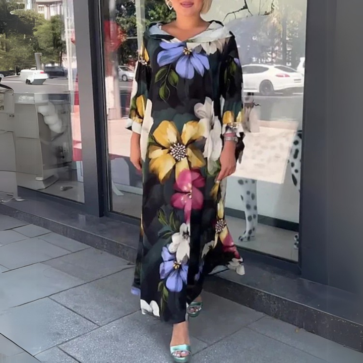 Frau in langem, geblümtem Kleid vor Schaufenster. Elegantes Design, bunte Blumenmuster, modische Sommerkleidung, Stadtbummel.