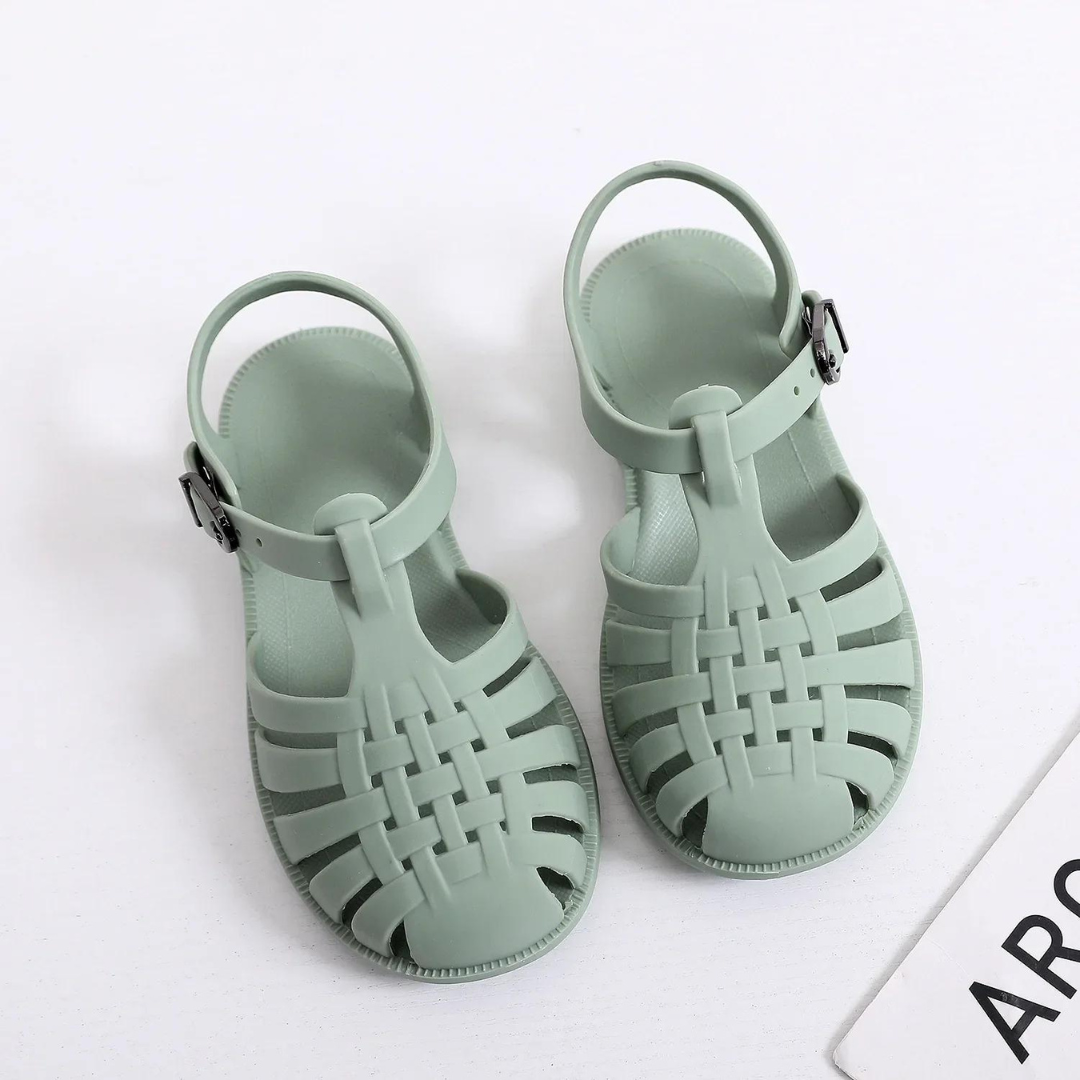 Grüne Sandalen aus Kunststoff mit geflochtenem Design und verstellbarer Schnalle auf weißem Hintergrund. Ideal für Sommermode und Strand.