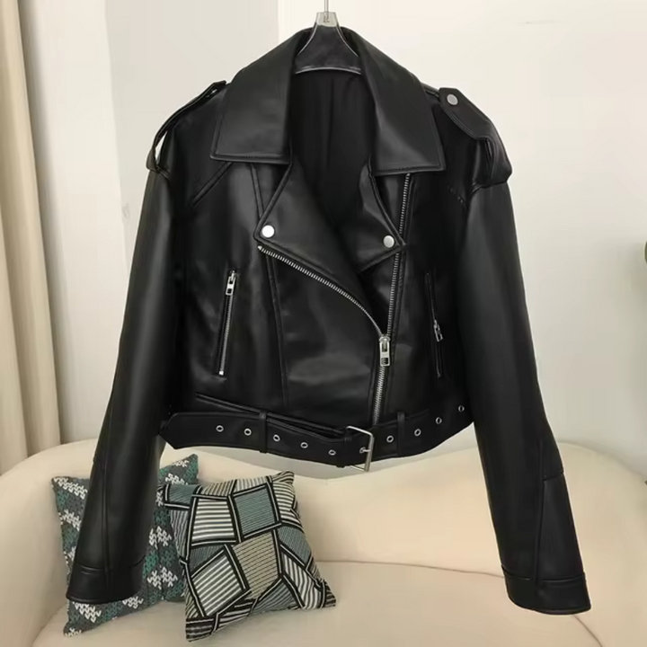 Schwarze Lederjacke mit Reißverschlüssen und Gürtel, hängt auf einem Kleiderbügel. Perfekt für Biker-Look und modische Outfits.