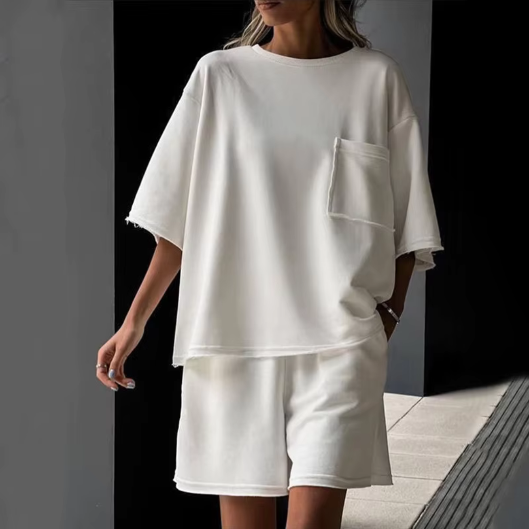 Frau in weißem Oversize-T-Shirt und Shorts, lässige Sommermode, minimalistisch, urbaner Stil, moderne Damenbekleidung, entspannter Look.