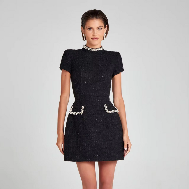 Schwarzes Tweed-Kleid mit kurzen Ärmeln und Perlenverzierungen, getragen von einer Frau. Elegantes Design, ideal für formelle Anlässe.