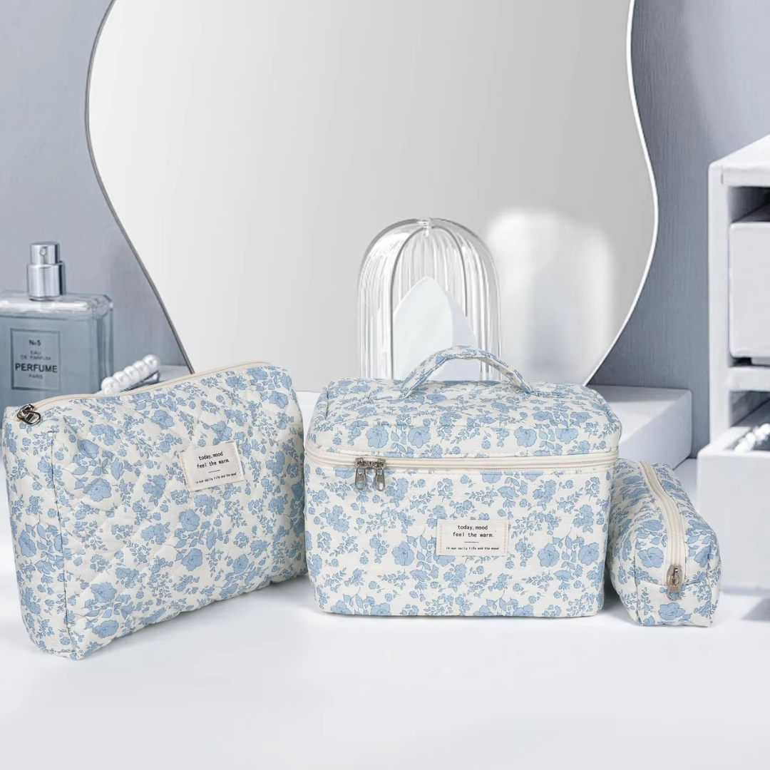 Drei blaue Blumenmuster-Kosmetiktaschen vor einem Spiegel, ideal für Reisen und Make-up-Aufbewahrung. Perfekt für stilvolle Organisation im Badezimmer.