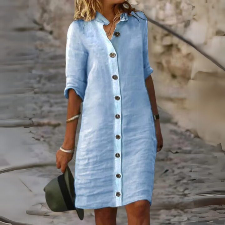 Blaues Leinenkleid mit Knopfleiste, lässiger Stil, getragen von Frau im Freien. Sommermode, bequemes Freizeitoutfit, ideal für warme Tage.