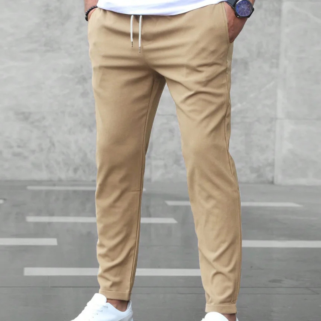 Beige Chino-Hose für Herren, kombiniert mit weißen Sneakern. Moderne Herrenmode, lässiger Stil, ideal für Freizeit und Alltag.