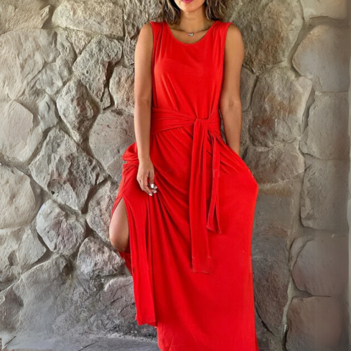 Frau in rotem Maxikleid vor Steinwand, modisches Sommeroutfit, elegantes Design, ärmelloses Kleid, rotes Kleid mit Gürtel, stilvolle Damenmode.