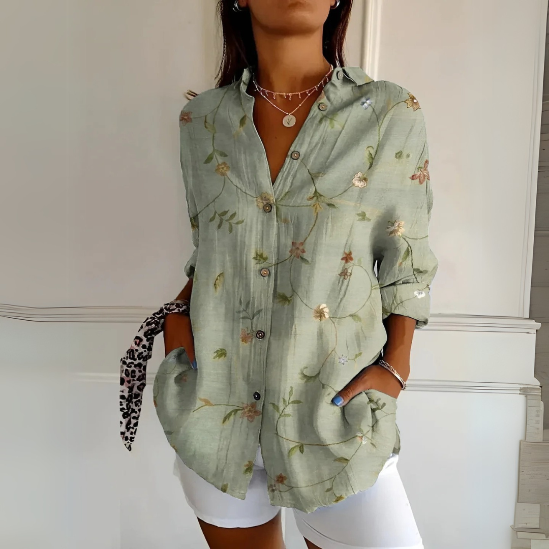 Frau trägt grüne, geblümte Bluse mit Knöpfen und weißen Shorts. Modetrend, Sommeroutfit, lässiger Stil, Damenmode, florales Design.