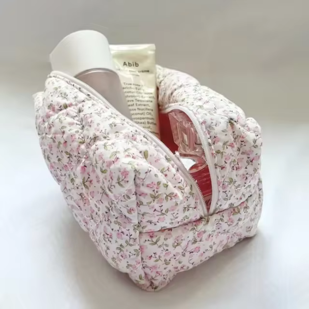 Gepolsterte Kosmetiktasche mit Blumenmuster, gefüllt mit Hautpflegeprodukten. Ideal für Reisen und Aufbewahrung von Kosmetikartikeln.